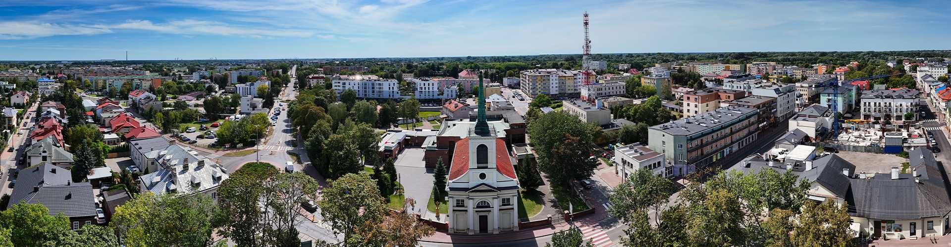 Kościół, domy jednorodzinne, bloki i ulice z lotu ptaka.