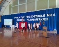 hala sportowa, dzieci ubrane na galowo idą ze sztandarem