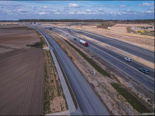 Cysterna i pięć samochodów osobowych jadących na drodze czteropasmowej.