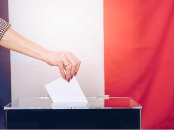 Ręka wkładająca kartkę papieru do urny.