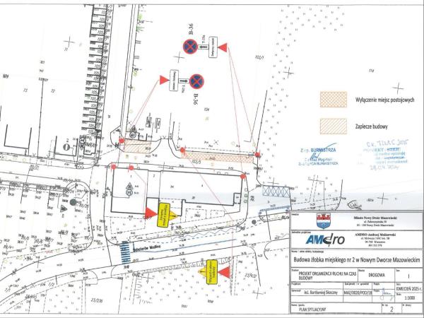 Plan z zarysami budynków i ulic ze znakami drogowymi.