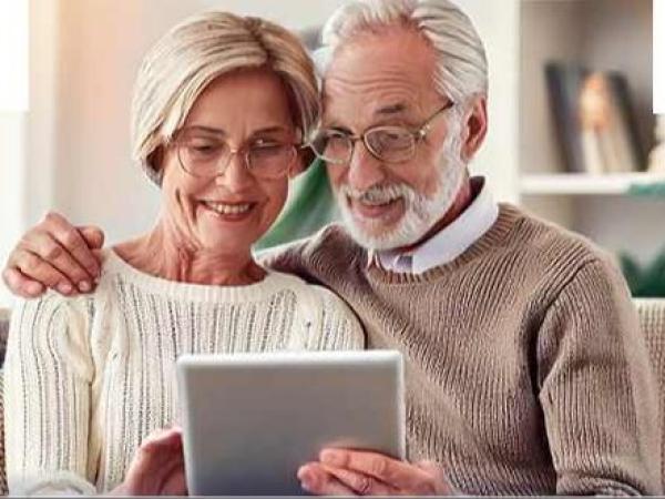 Kobieta i mężczyzna patrzą w tablet trzymany wspólnie w dłoniach.