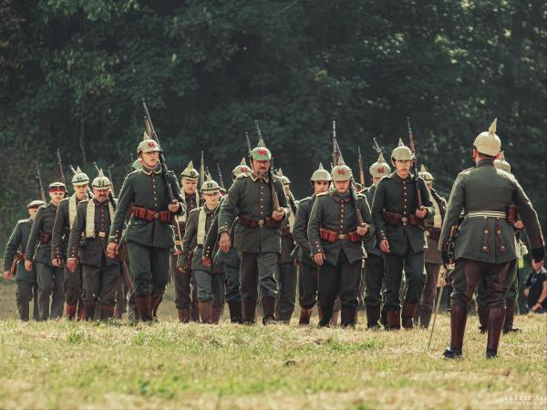 Kilkunastu mężczyzn maszerujących z bronią w mundurach wojskowych z I wojny światowej.