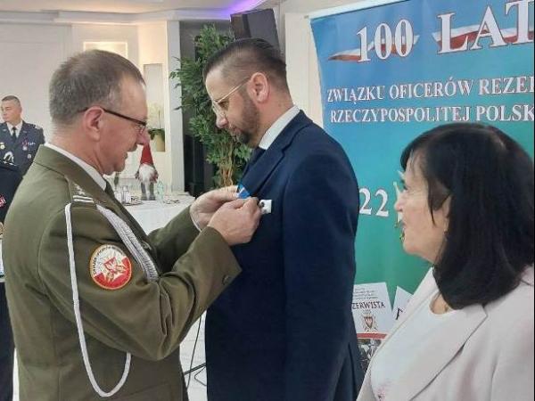 Mężczyzna w mundurze wojskowym przypina medal mężczyźnie w garniturze.